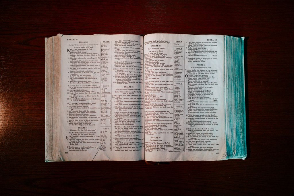An open Bible displaying the Book of Psalms laid on a wooden table, captured from above.